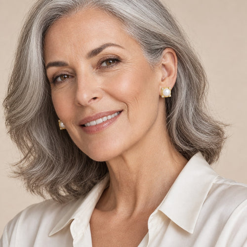 Woman in her sixties wearing the Agatha square frame pearl studs, hair tucked behind her ear