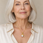 Woman wearing the Agnes gold cap pearl and star charm pendant necklace at the sternum with a navy sweater