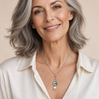 Woman wearing the Alma Christmas tree pearl pendant necklace at the sternum over a cream cable-knit sweater