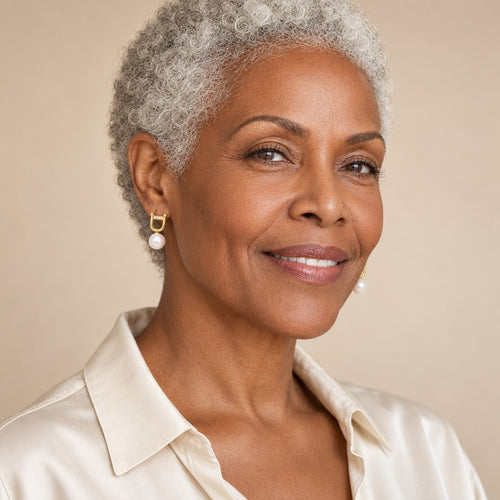 Woman in her forties wearing the Chantal shackle pearl drop earrings, hair tucked behind her ear