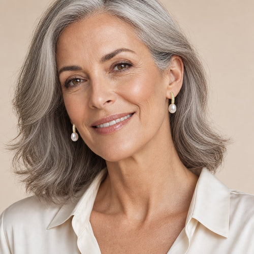 Woman in her fifties wearing the Clemence curved bar pearl earrings, hair up