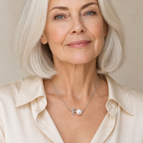 Woman wearing the Dagny leaf sprig pearl necklace at the collarbone with a natural linen shirt