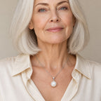 Woman wearing the Diana single pearl pendant necklace at the collarbone with a black boat-neck top