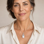 Woman wearing the Elin pavé leaf crown pearl pendant necklace at the sternum with a black crew-neck dress