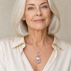 Woman wearing the Linnea lavender pearl pendant necklace at the sternum with a light gray V-neck blouse