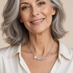 Woman wearing the Lydia pavé feather pearl necklace at the collarbone with a black velvet off-shoulder top