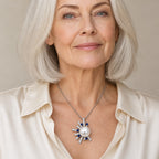 Woman wearing the Marian pavé sunburst pearl pendant necklace at the sternum with a black crew-neck top