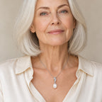 Woman wearing the Sybil pavé twist rice pearl pendant necklace at the collarbone with a black top
