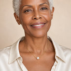 Woman wearing the Winifred floating pearl box chain necklace at the collarbone with an off-shoulder cream top